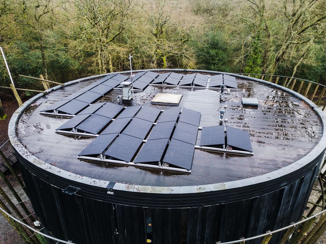 Mastering the First Impression: Your intriguing post title goes here Aerial view of a round rooftop with solar panels surrounded by trees, promoting renewable energy.