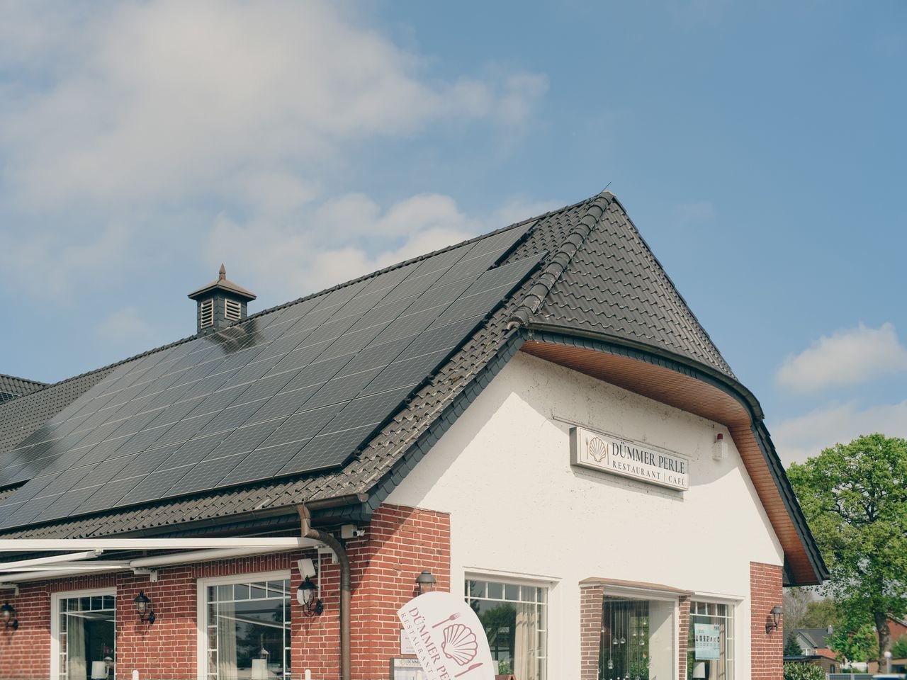 The Art of Drawing Readers In: Your attractive post title goes here A red brick building with solar panels on the roof, under a clear blue sky, symbolizing sustainability and renewable energy.